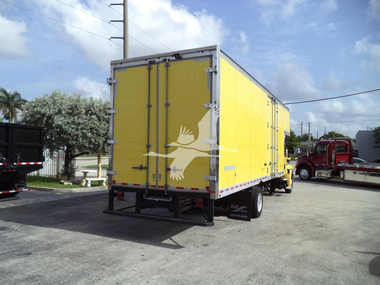 Yellow box truck trailer with rear doors, in-service Moving Van on a lot. Visible text/labels include no explicit model or brand text on the back, only standard reflective markings.