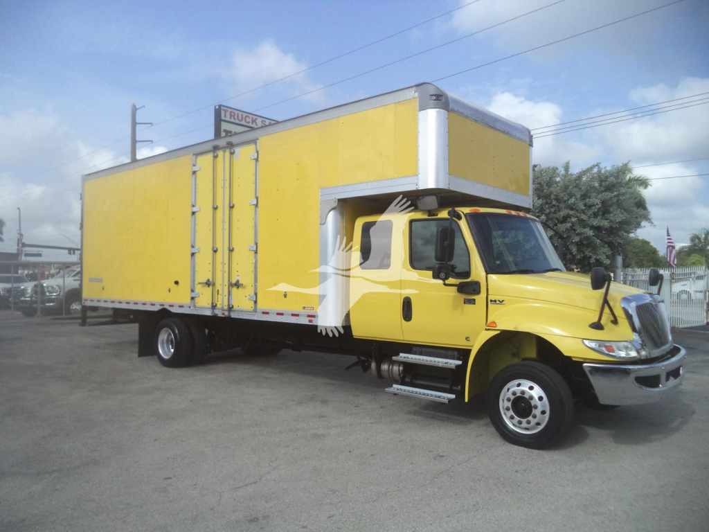 Yellow 2020 International MV moving van with long box cargo area and cab; visible details include VIN and stock in listing context.