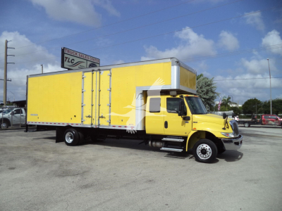 Truck in a bright yellow box truck with a yellow cab, moving van body, side doors closed, on a paved lot.