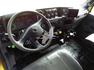 Truck cab interior showing steering wheel, dashboard, and control panel. Dashboard gauges visible; no readable labels or numbers clearly legible.