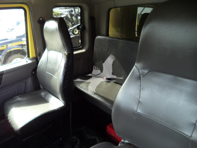 Interior of a 2020 International MV moving truck showing front passenger seat and rear bench seat with black upholstery.