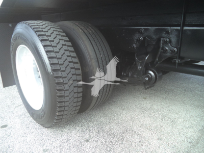 Dual rear axles with leaf spring suspension and large dual tires; chassis and mounting hardware visible.