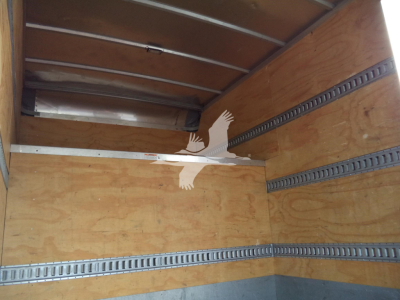 Truck cargo area interior showing wooden walls and aluminum E-track rails.