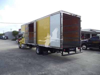 Truck with a large box trailer, rear and side view showing loading doors and interior walls. Visible text on the trailer includes faded graphics and possible branding, no legible model details.