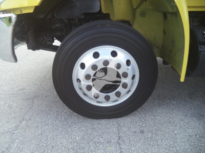 Wheel and tire of a yellow moving van with chrome hubcap and multiple lug nuts visible.