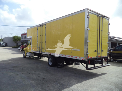 Box truck with bright yellow moving van trailer attached to a yellow cab, logo of a white bird on the side, rear doors closed, in a dealership lot.
