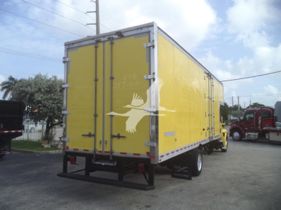 Yellow cargo box truck trailer with rear double doors showing metal latches, white bird graphic on doors, and reflective tape along edges; black bumper and wheel wells visible.