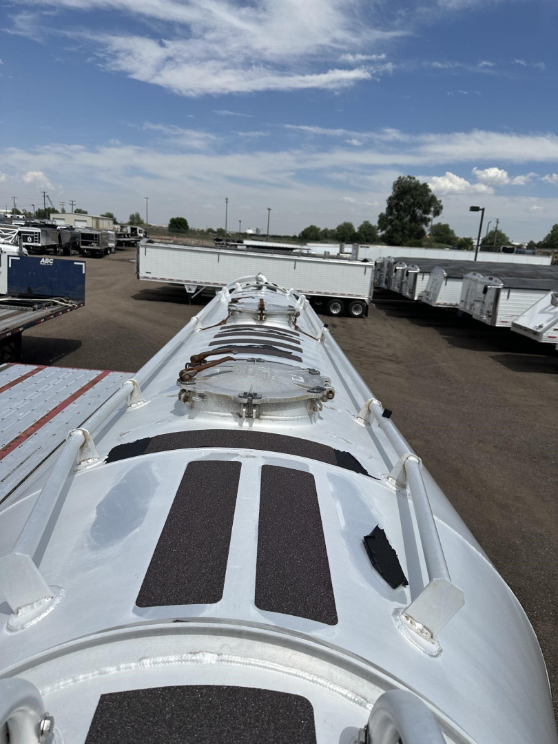 Pneumatic trailer top view showing multiple manways and hatches on a silver cylindrical tank in a yard.