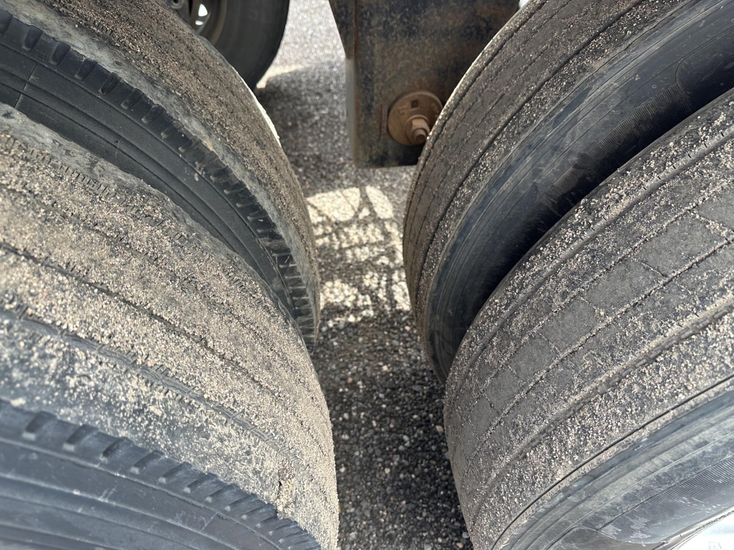 Wheel set of a Polar Gravity Drop Pneumatic trailer showing two rear dual tires; tread visible with dirt and wear.