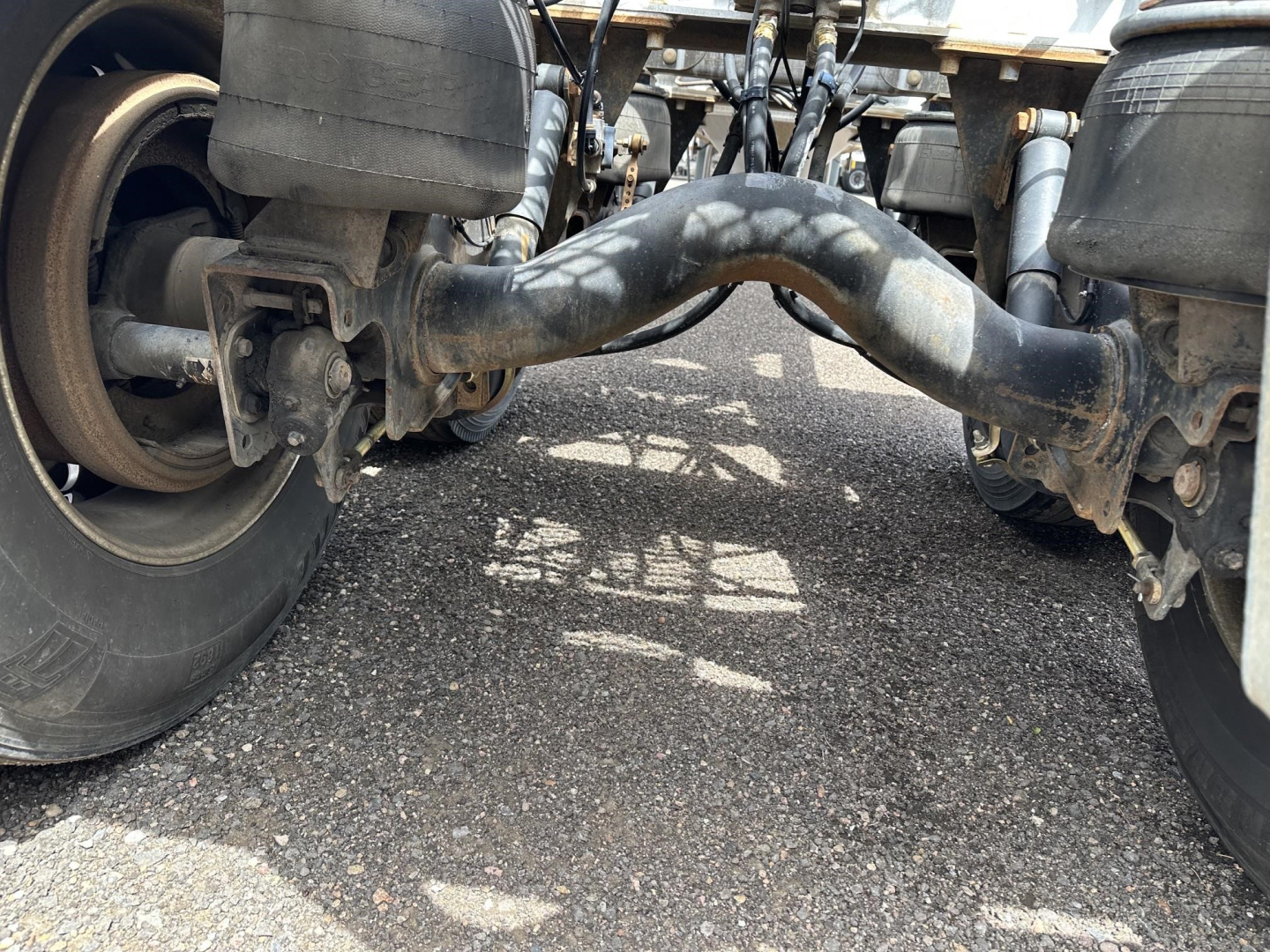 Underbelly of a Polar Gravity Drop Pneumatic trailer showing maneuvering hitch and dual landing gear with thick suspension pipes visible.