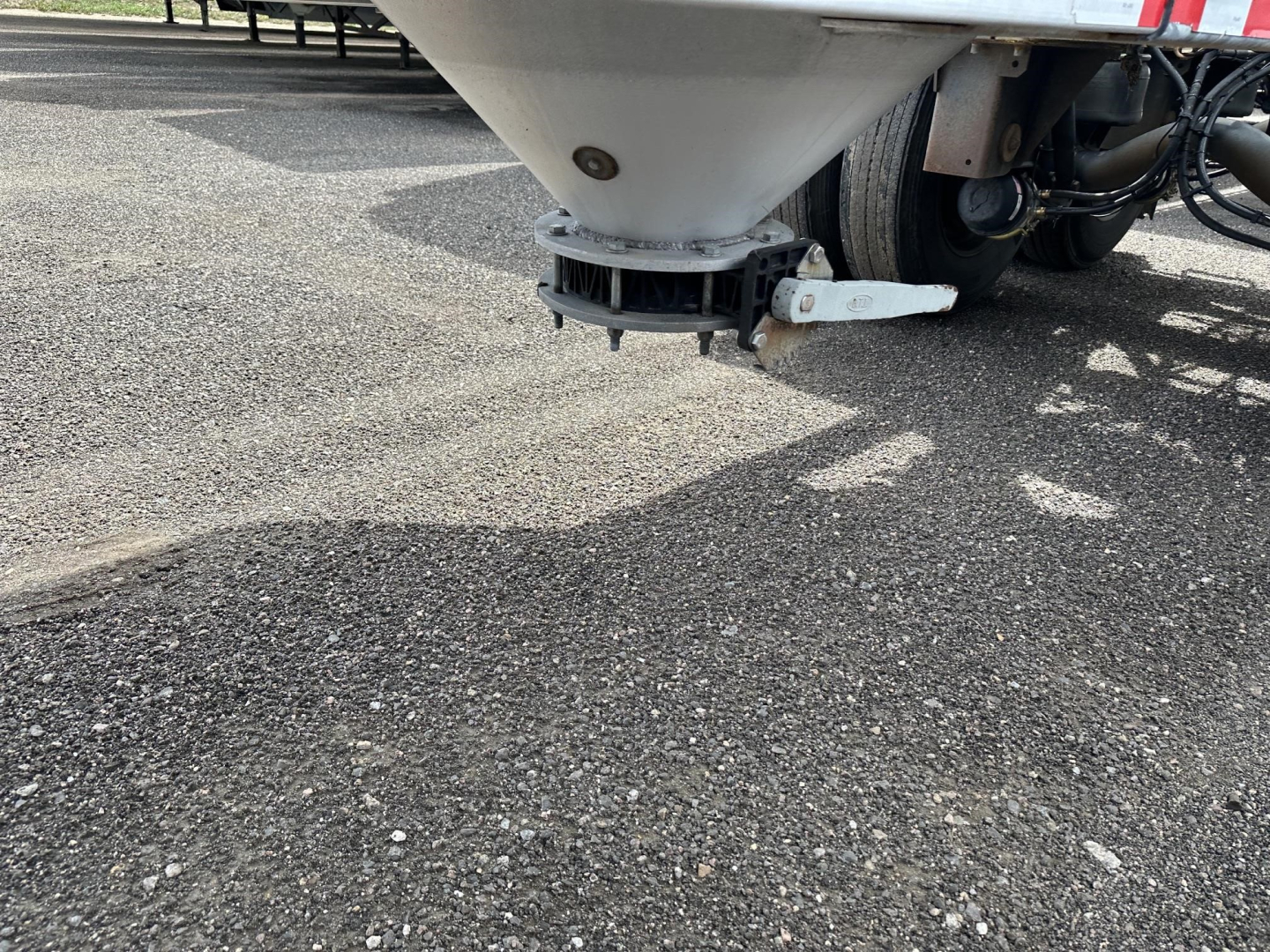 Pneumatic gravity drop trailer undercarriage showing dumping device and low-angle view of underside; visible components include hopper outlet and hitch area.