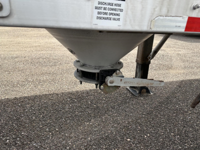 Trailer underside showing discharge valve and hitch on a Polar Gravity Drop pneumatic trailer. Text on label: DISCHARGE HOSE MUST BE CONNECTED BEFORE OPENING DISCHARGE VALVE.