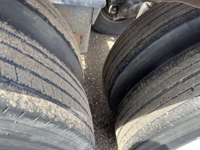 Trailer tires and undercarriage view from above, showing two large tires with tread, part of a pneumatic-dry bulk trailer.