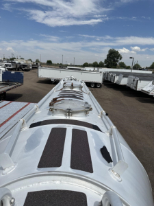 Pneumatic trailer top view showing multiple manways and hatches on a silver cylindrical tank in a yard.