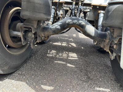 Underbelly of a Polar Gravity Drop Pneumatic trailer showing maneuvering hitch and dual landing gear with thick suspension pipes visible.