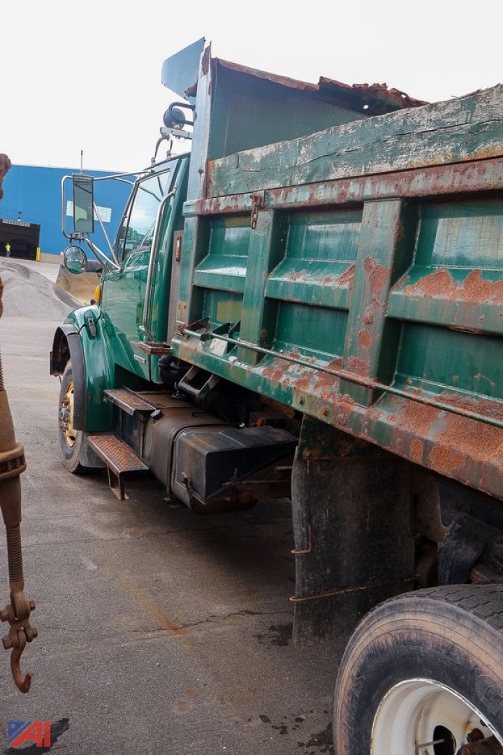 Dump truck bed and cab of a used 2003 Sterling Acterra with green exterior and rust-streaked bed, side view showing hydraulic dump mechanism and rear wheel.