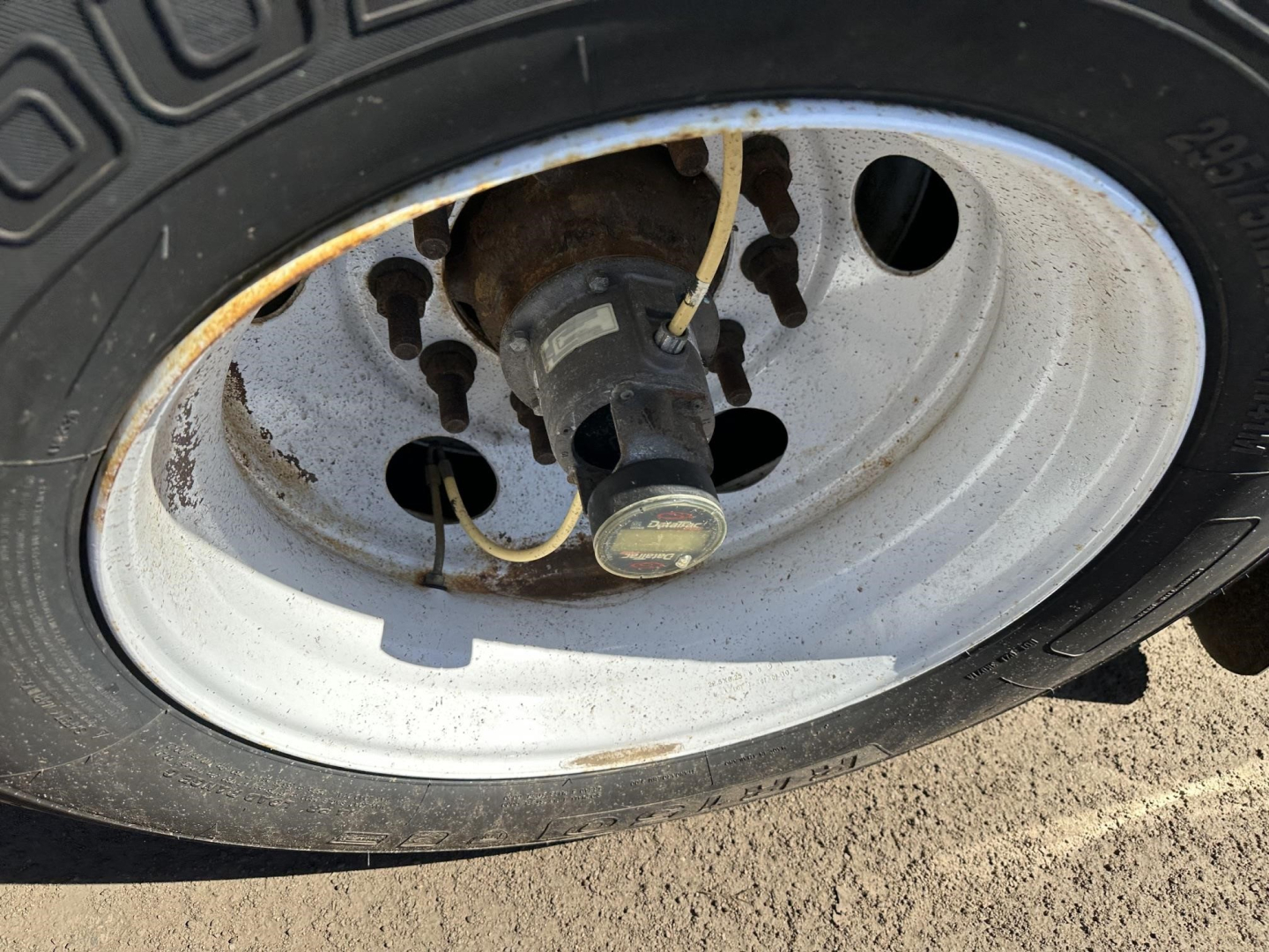 Wheel and hub of a trailer with a metal rim, tire, and valve stem visible.
