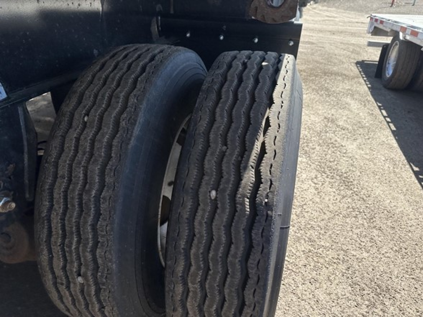 Trailer dual rear tires of a Fontaine Infinity flatbed trailer showing tread pattern and wheel wells.