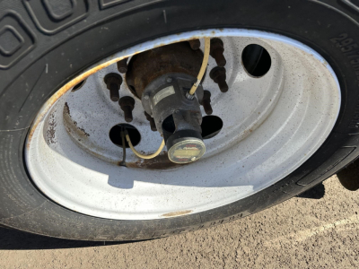 Wheel and hub of a trailer with a metal rim, tire, and valve stem visible.