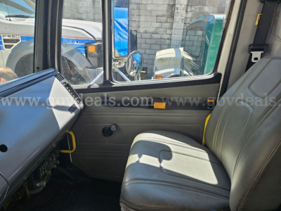 Cab interior of a 1999 Freightliner FL106 showing driver's seat and dashboard with window view
