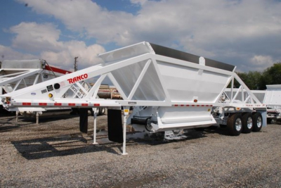 Ranco low-weight bottom dump trailer on a three-axle chassis with white frame and hopper, parked outdoors.
