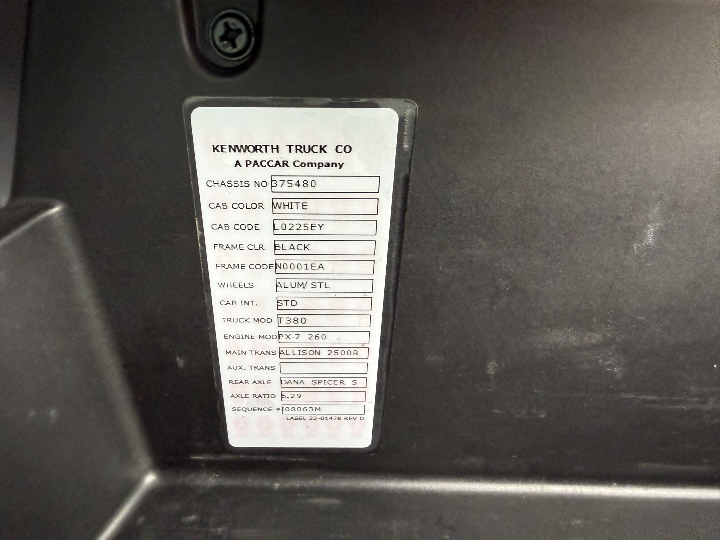 Kenworth truck chassis tag showing model and spec details: CAB COLOR WHITE, CHASSIS NO 75480, TRUCK MOD T380, ENGINE MT 9.3L? (text partial) MAIN TRANS ALLISON 2500R, WHEELS ALUM/STL