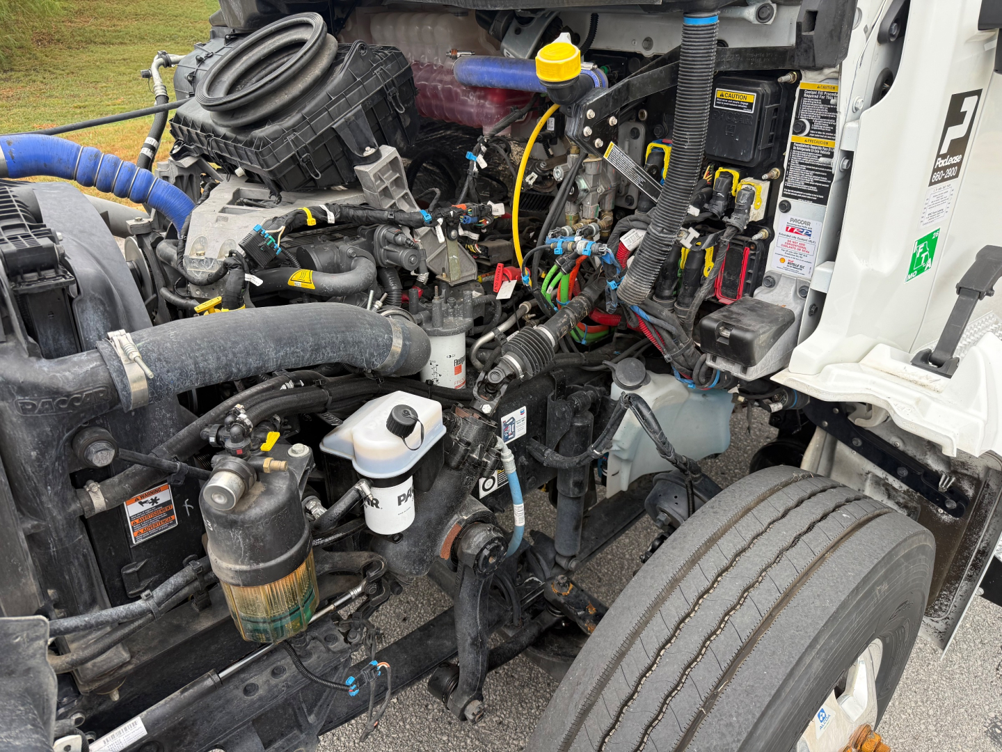 Kenworth T380 engine bay showing various components, hoses, wiring, yellow dipstick, coolant reservoir, and air filter housing.