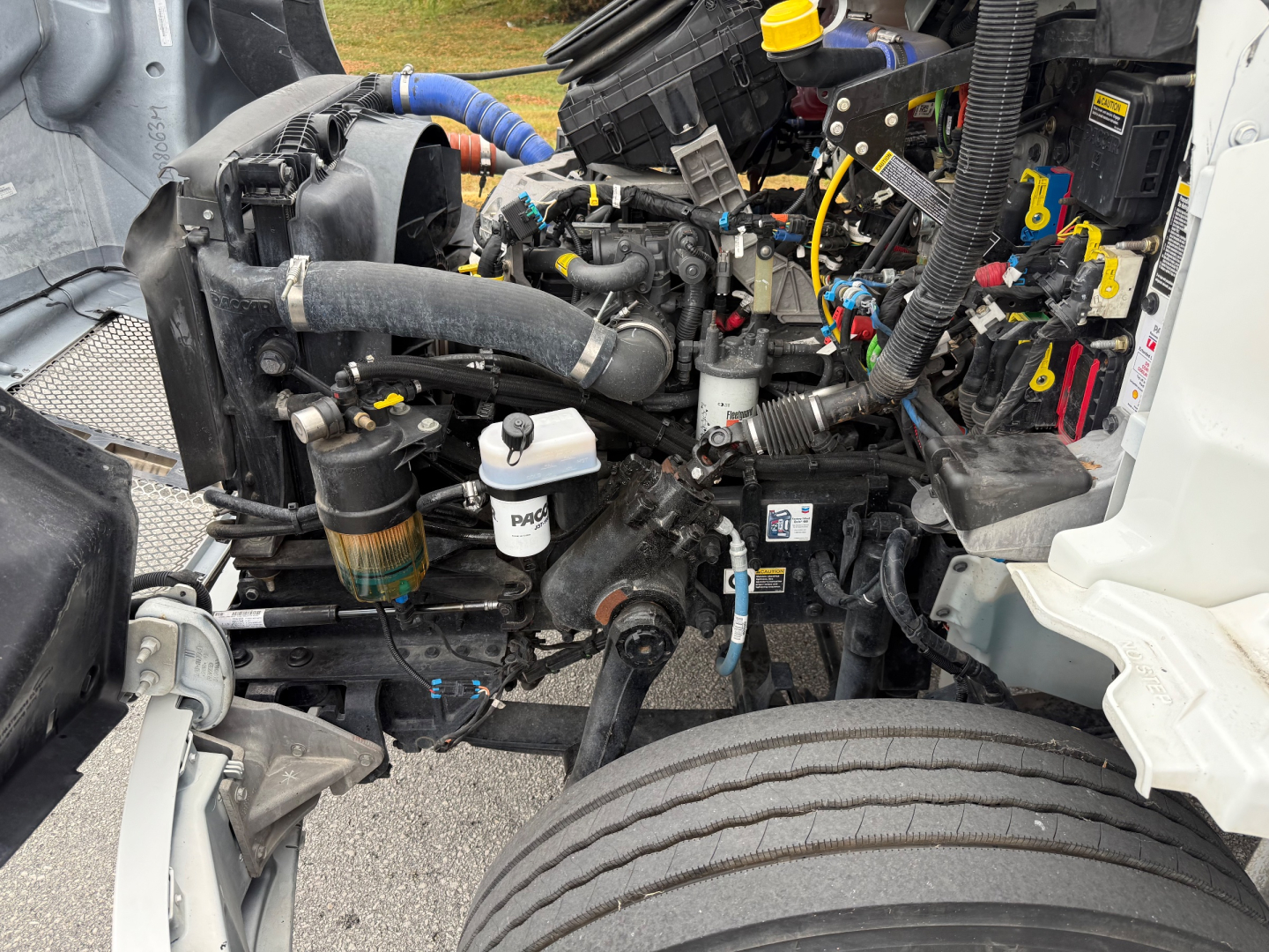 Engine bay of a 2024 Kenworth T380 (box truck) showing components, hoses, wiring, and reservoir caps.