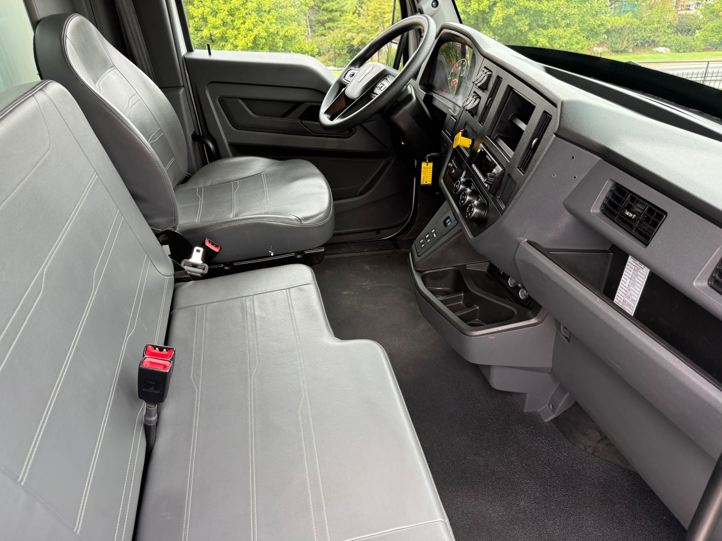 Kenworth T380 interior view showing front bench seat, steering wheel, dashboard, and center console with gauges and controls.