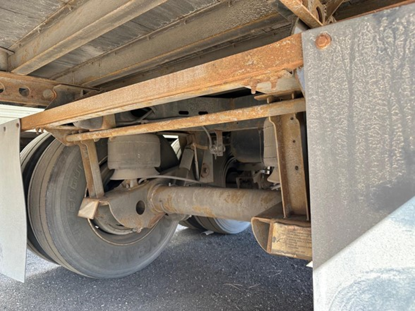 Trailer undercarriage showing rear axle and suspension with air ride components and dual tires.