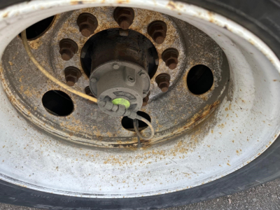 Wheel hub and rim of a 53' dry van trailer with visible rust on the steel wheel and hub, showing the central hub and lug nut holes.