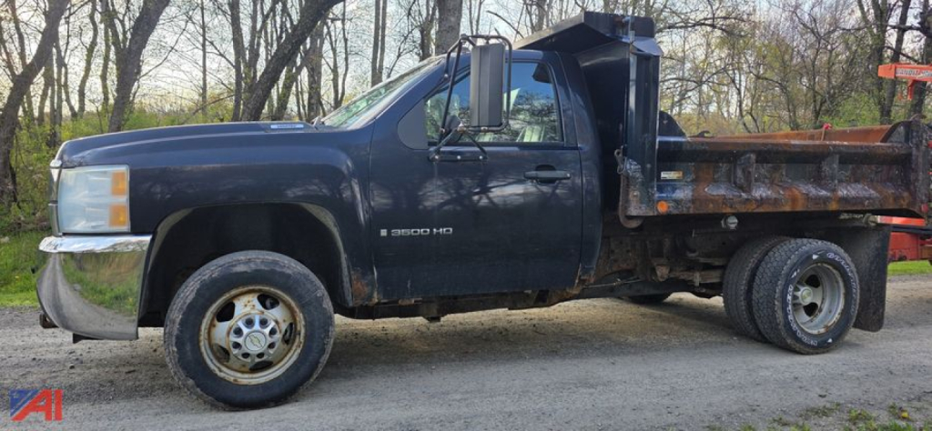 Chevrolet Silverado 3500HD dump truck side view showing dump bed and dual rear wheels with visible rust and utility bed.