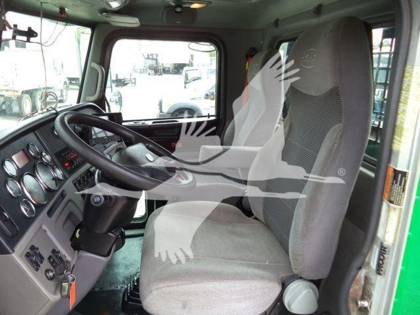 Truck cab interior showing steering wheel and driver's seat with dashboard gauges and controls.