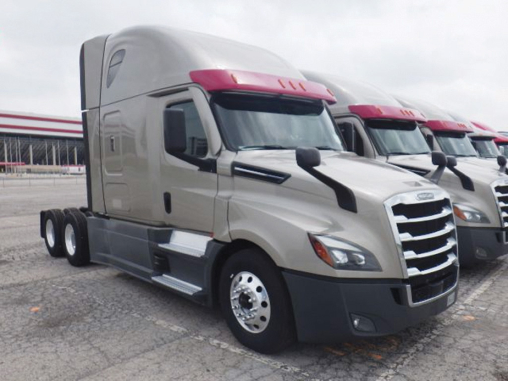  Freightliner Cascadia126 truck cab in view with tan color and red fairings showing chrome grille and wheels.