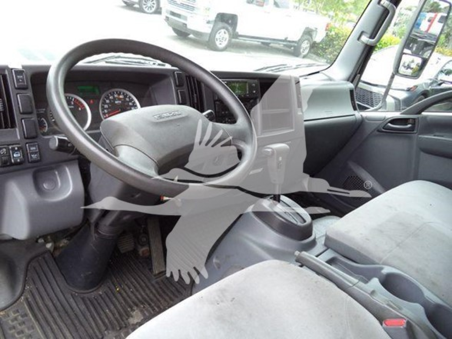 Isuzu NQR truck cockpit showing steering wheel and dashboard with center console and driver seat in view.
