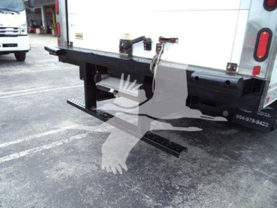 Isuzu NQR rear view showing black drop-down steel bumper/step with mounting brackets and latching hinges on a refrigerated truck.
