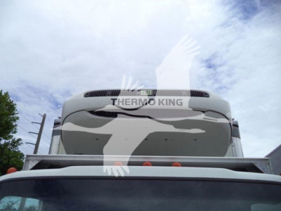 Isuzu NQR truck cab front view showing Thermo King unit on top of refrigerated body. Clear sky with clouds.