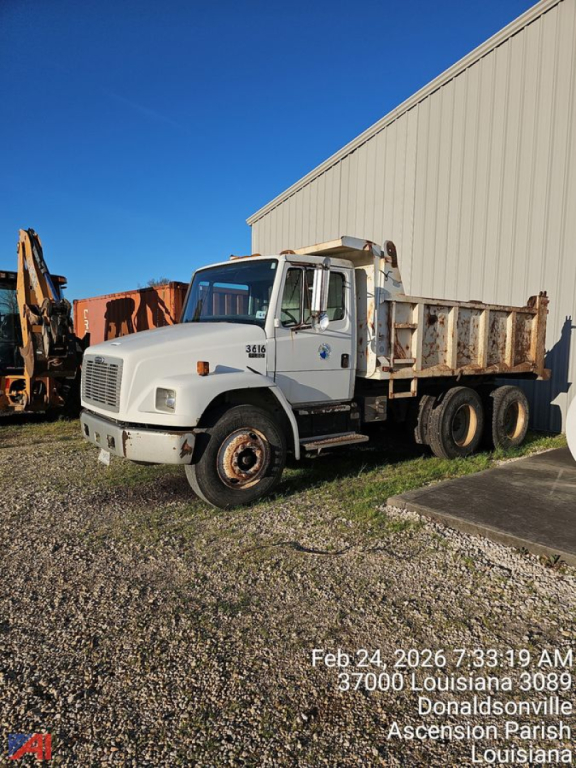 Dump truck cab and bed of a 2003 Freightliner FL80 in-service showing front grille, headlights, and triple rear axles with a metal dump bed.