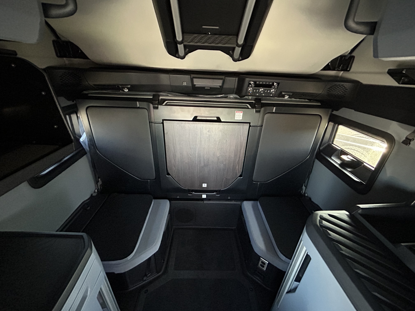 Cab interior of a new 2027 Mack PR64T76H sleeper truck showing front dash controls and seating area with overhead console.