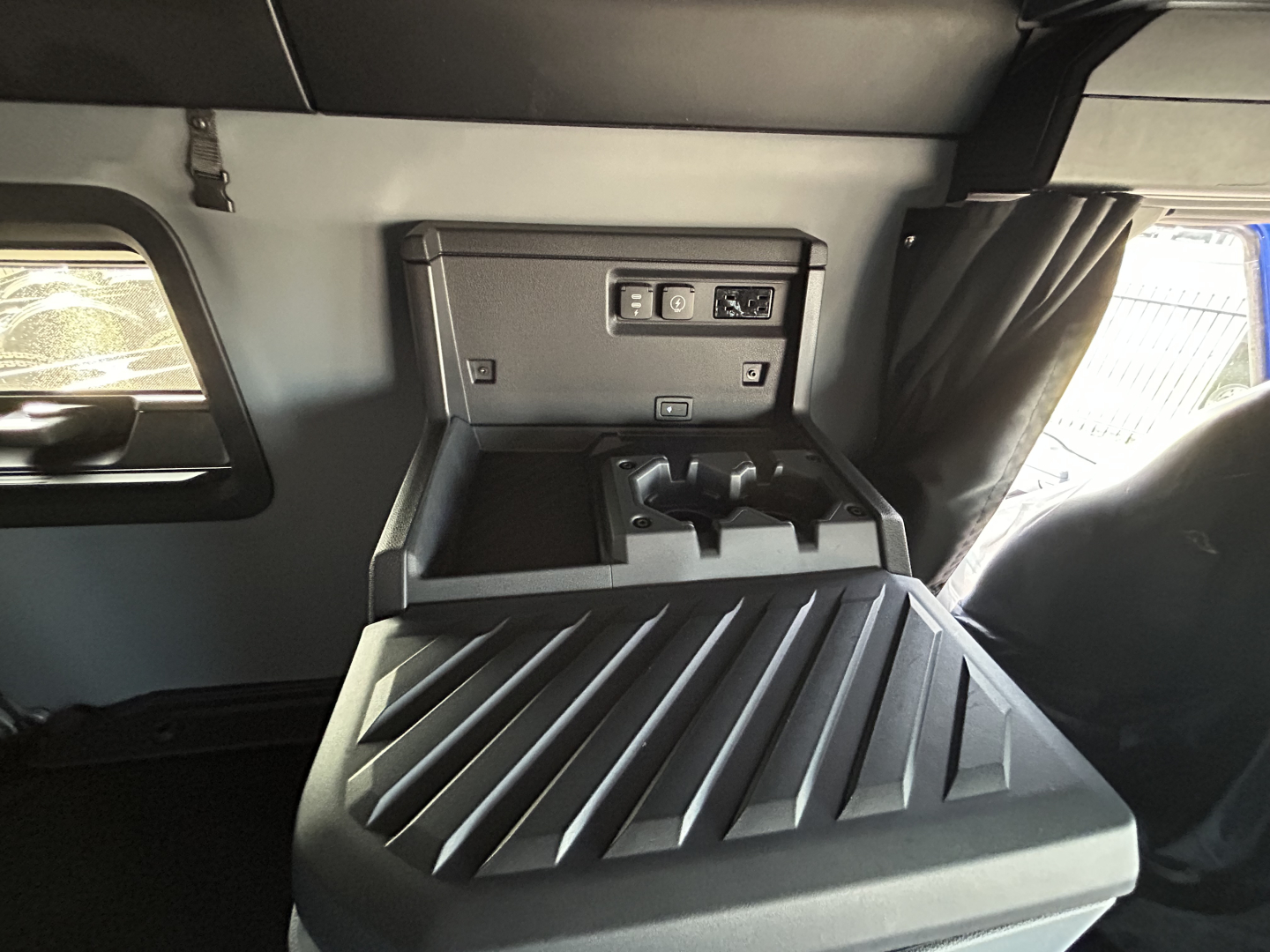 Truck cab interior showing storage console and side window with sunshade; control panel and cup holders visible.