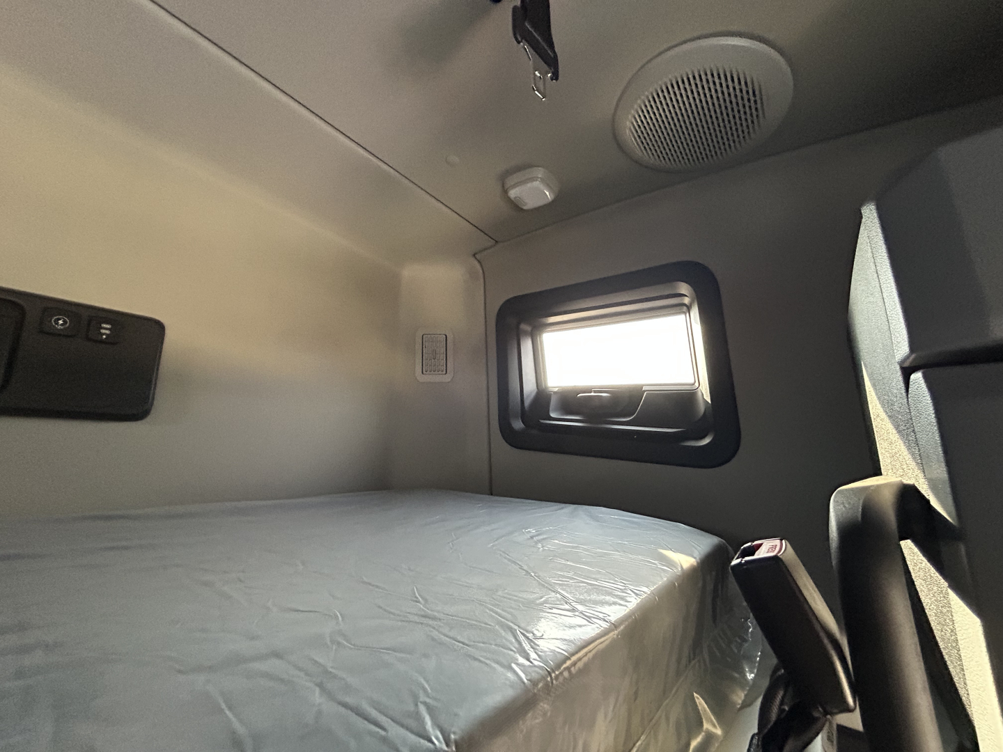 Mack PR64T76H sleeper cab interior showing bed area and window with speaker above.
