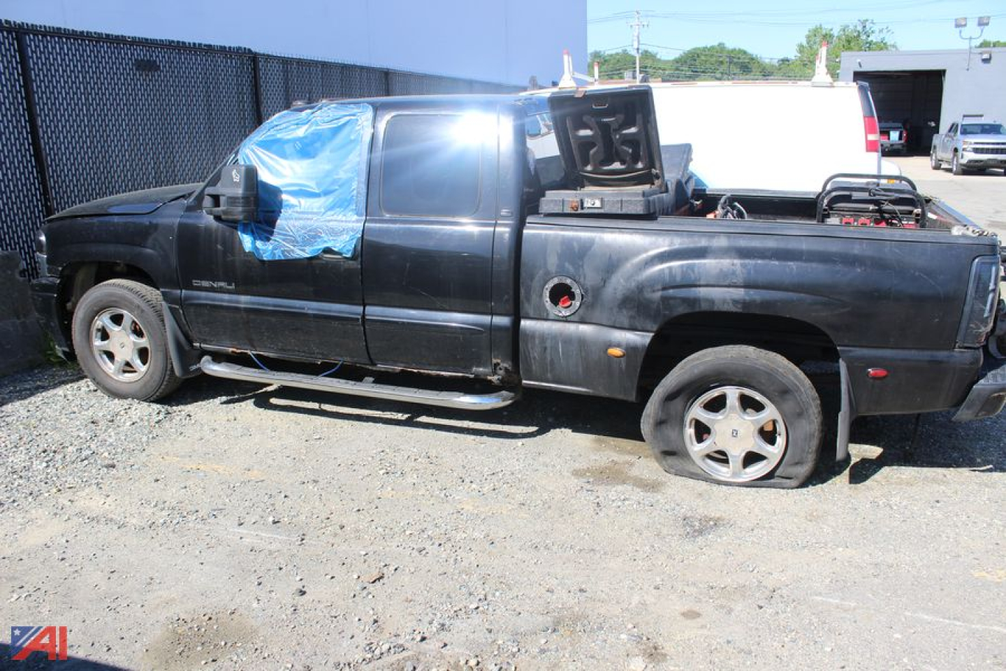 GMC Sierra 1500 extended cab pickup truck side view showing damaged cab windows and missing doors, black color, with truck bed and rear wheel visible.