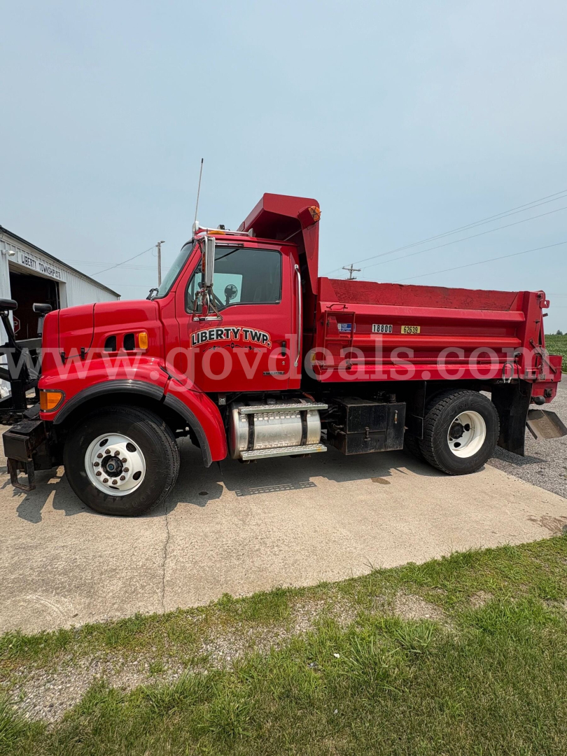 Dump truck showing side view of a red 2004 Sterling L7500 with Liberty TWP lettering and dump bed, VIN 2FZAATAK34AM63427.