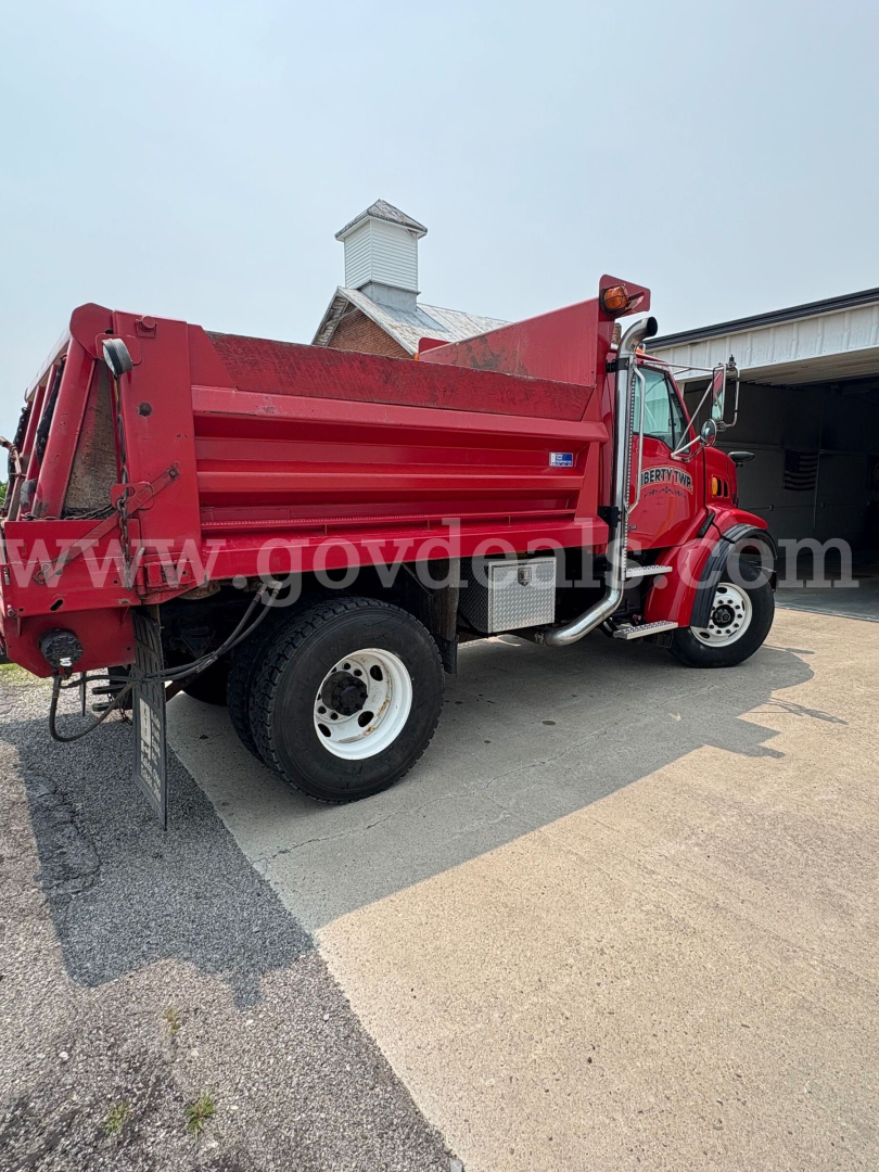 Dump truck side view showing red Sterling L7500 with dump bed, wheel tires, and cab details.