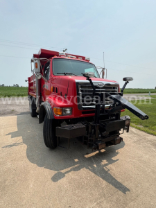 Front view of a red 2004 Sterling L7500 dump truck with a plow attachment and equipment on the front bumper.