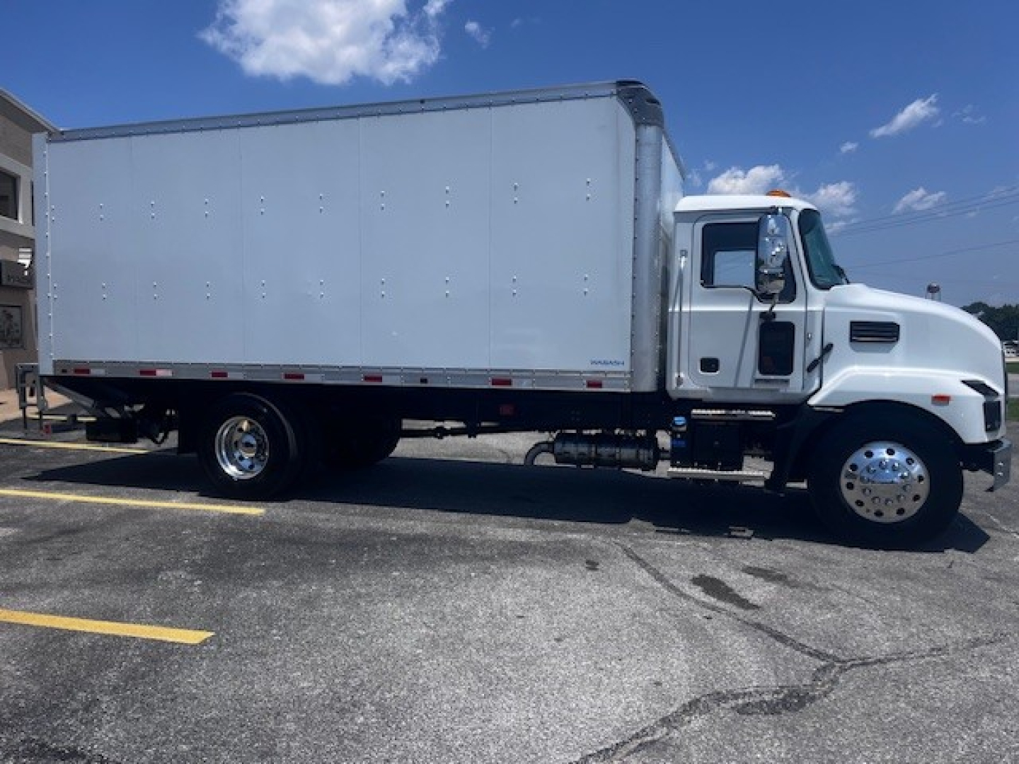 Box truck showing 2025 Mack MD6 with white cab and cargo box, side view.