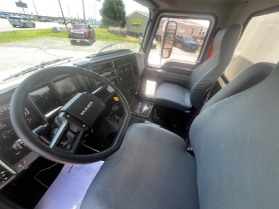 Truck cabin interior showing steering wheel with Mack logo, dashboard, driver seat, and front passenger seat of a 2025 Mack MD6.