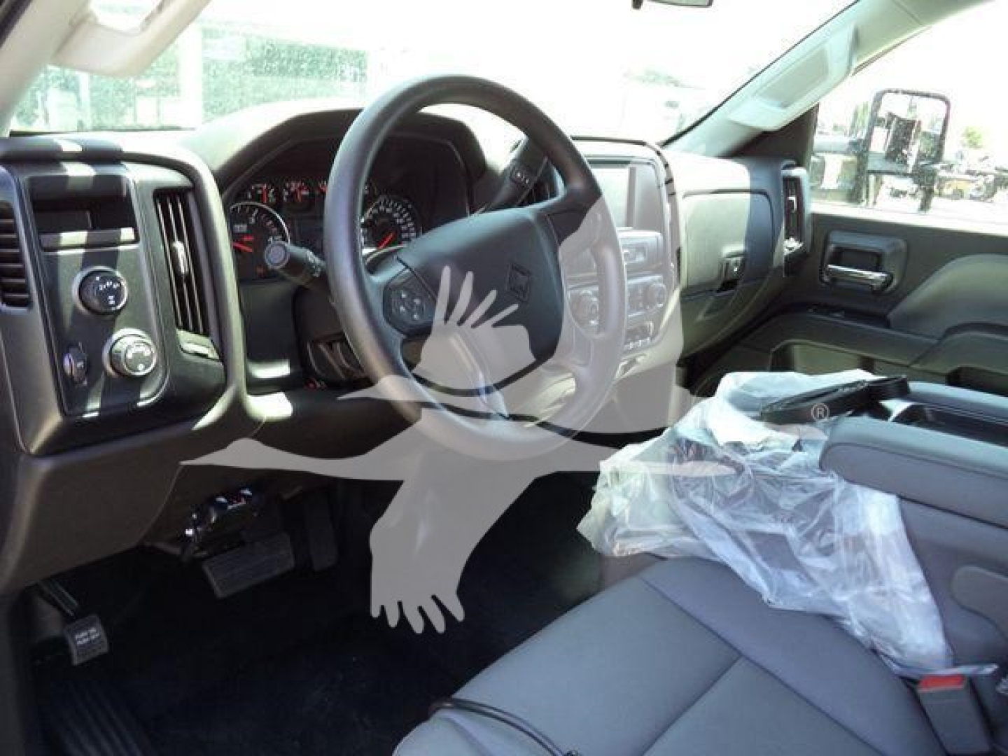 Truck interior showing steering wheel, dashboard, and front seats with protective plastic on the passenger seat; instrument cluster and control panels visible.