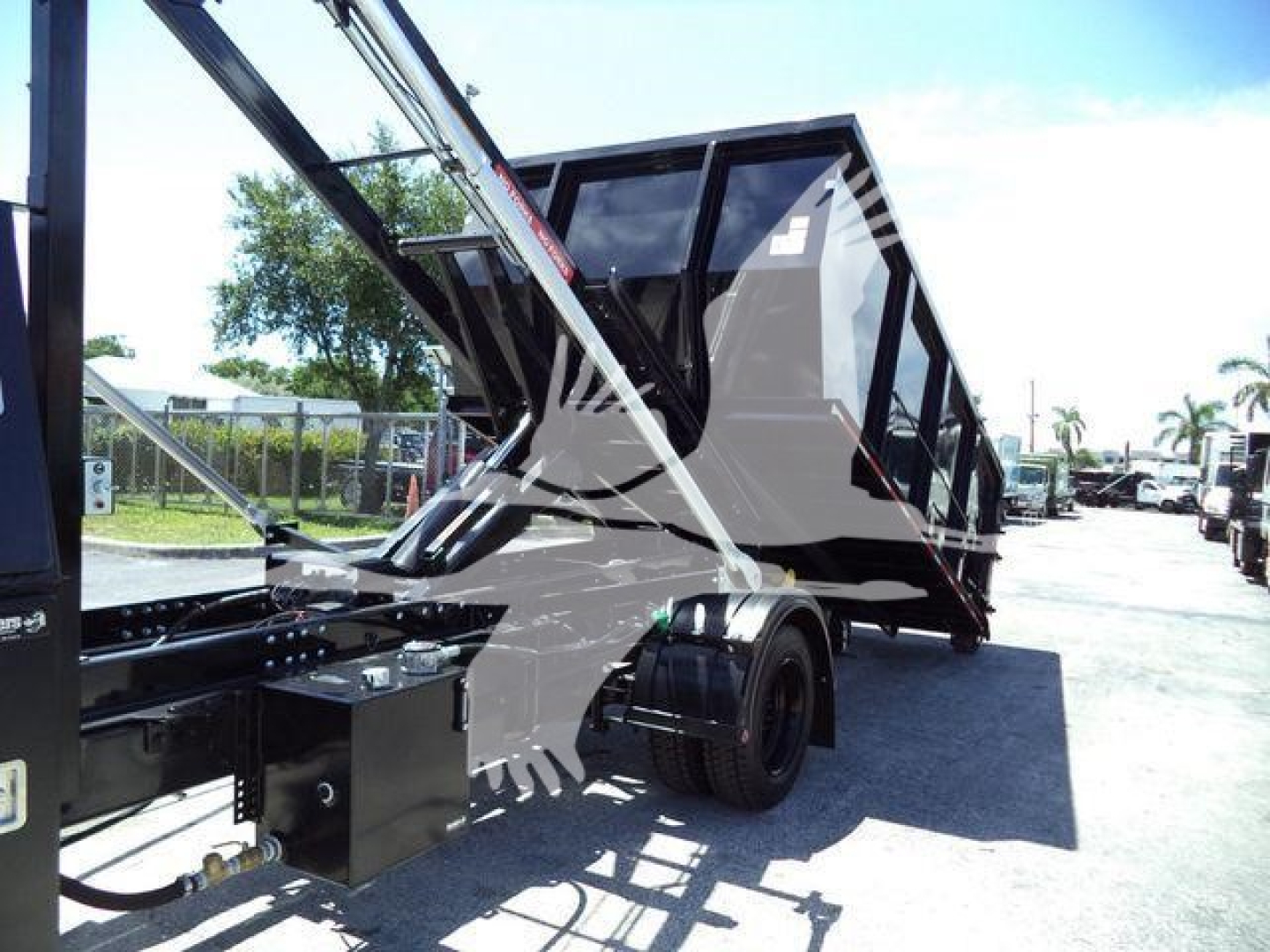 Equipment image showing a new 2023 International CV roll-off truck with a dumping container and hydraulic arms.