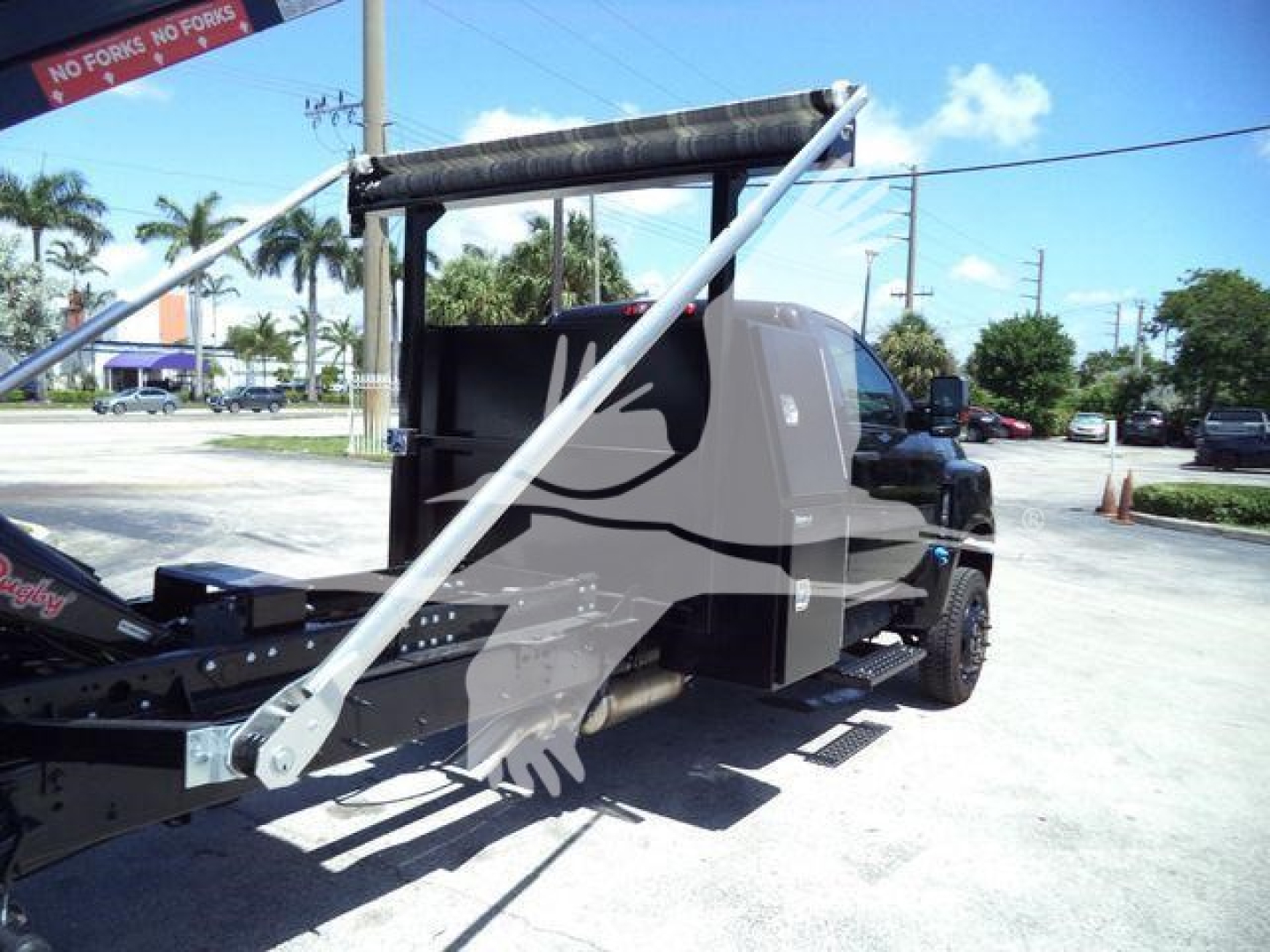 Truck cab and rollout equipment on trailer showing hydraulic piping and structural bars with a gray cab and black chassis.